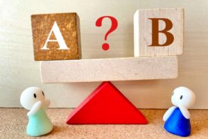 Two small figurines watch a balance with A on the left, B on the right, and a red question mark between.
