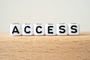 White lettered dice spell 'ACCESS' lined up on a wooden table.