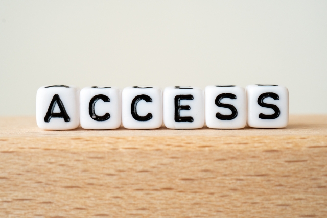 White lettered dice spell 'ACCESS' lined up on a wooden table.